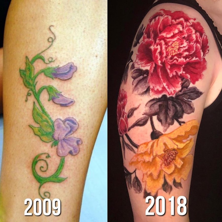 A bold and colorful floral tattoo on the upper arm, featuring large flowers in a watercolor style — by Sandra Price, los angeles