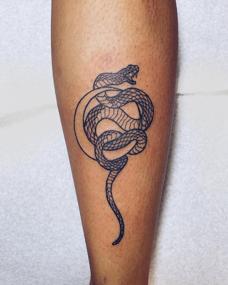 A minimal black linework snake tattoo on the calf, featuring a simple and elegant design — by Level tattoo, los angeles