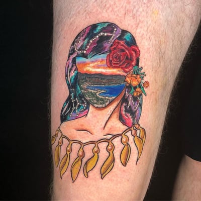 A colorful surreal tattoo of a woman with a landscape as her face, adorned with flowers, on the thigh — by Sandra Price, los angeles