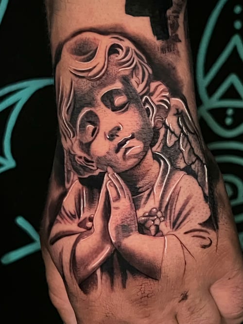 A black and grey realistic depiction of an angel with closed eyes and hands in prayer on the hand, featuring detailed shading and highlights — by Josue Bravo, los angeles