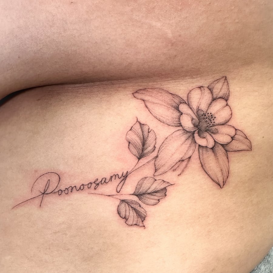 A delicate black and grey flower with script on the hip, featuring fine line details and soft shading — by Melanie Benoit, los angeles
