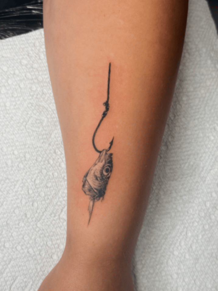 tiny black and grey fine-line tattoo of a fish skull on a fishing hook by lunay flores, a fine line tattoo artist in los angeles