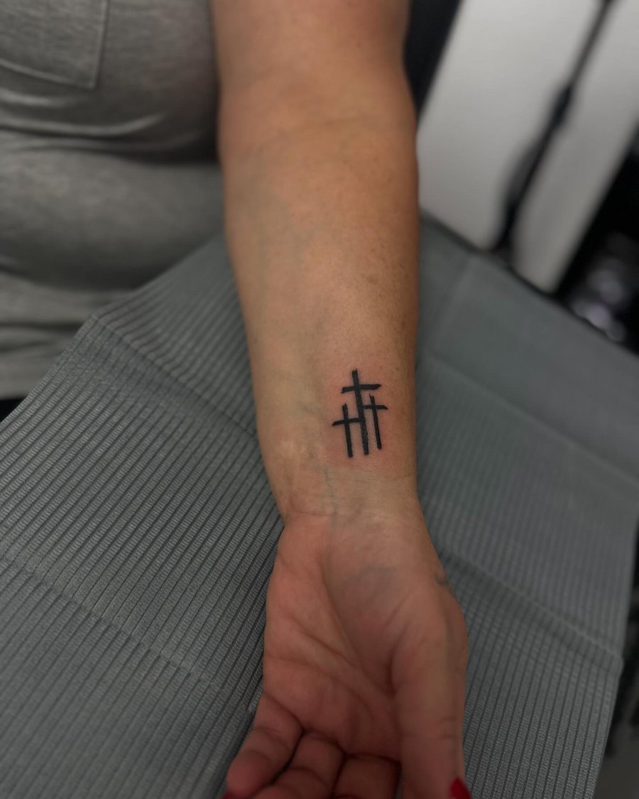 A bold blackwork tattoo of three minimalist crosses on the forearm — by Maddie Ramirez, los angeles