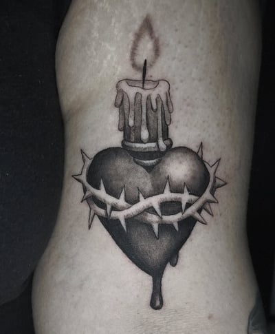 A black and grey tattoo of a heart with a candle on top and thorns wrapped around it, located on the arm — by Miguel ANGELO, los angeles