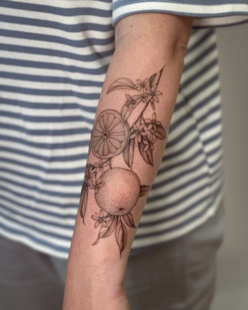 A delicate black and grey tattoo of an orange branch with fruit and flowers on the forearm, done in fine line style — by Melanie Benoit, los angeles