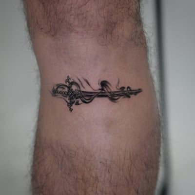A delicate black and grey ornate sword tattoo on the leg, featuring fine line details and intricate design — by Jian Liang, los angeles