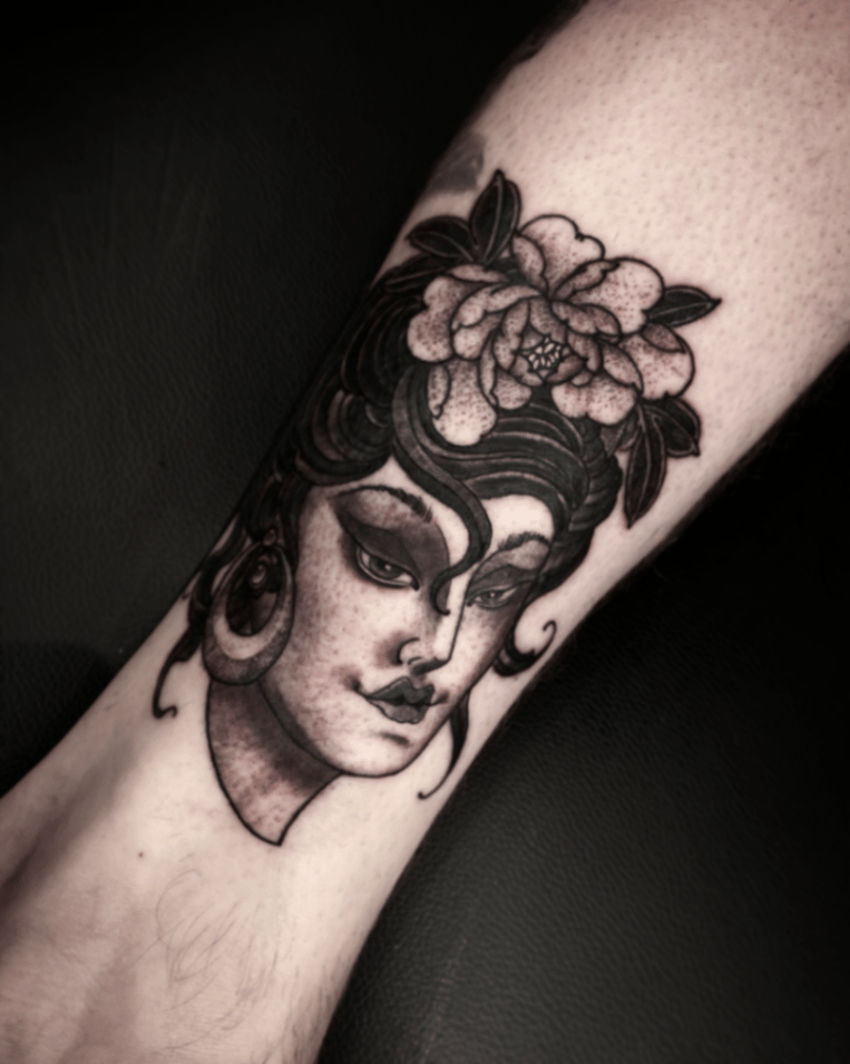 A black and grey neo-traditional tattoo of a woman's face with a flower in her hair on the leg, featuring bold lines and shading — by tyler_whitlock, los angeles