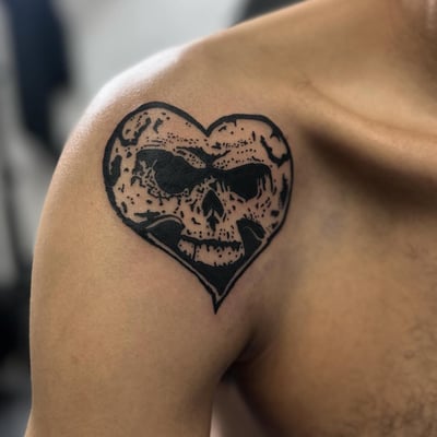 A blackwork heart-shaped skull tattoo on the shoulder with fine line details — by Maddie Ramirez, los angeles