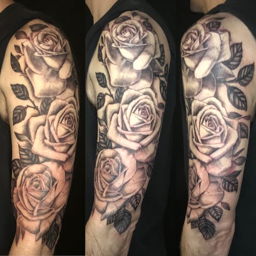 A bold black and grey rose bouquet tattoo on the upper arm with realistic shading and detail — by Sandra Price, los angeles