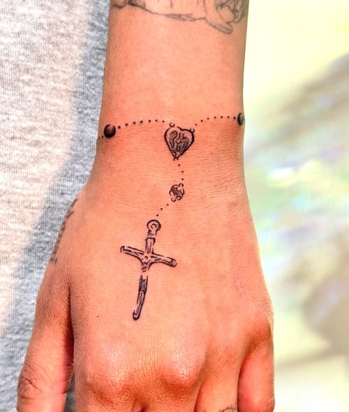 A minimalist black and grey tattoo on the hand featuring a dagger and a heart connected by a dotted line — by NJ TATTOOZ, los angeles