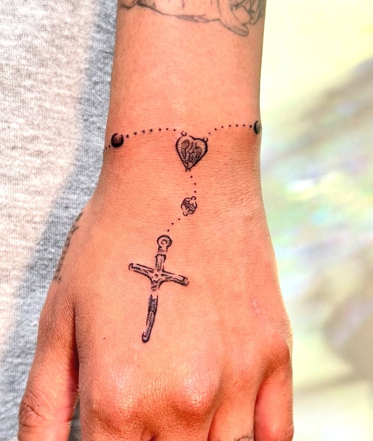 A minimalist black and grey tattoo on the hand featuring a dagger and a heart connected by a dotted line — by NJ TATTOOZ, los angeles