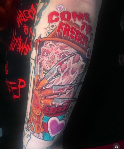 A colorful New School tattoo of Freddy Krueger on the forearm, featuring bold outlines and vibrant colors with the text 'Come to Freddy' — by Jessica Linden, los angeles