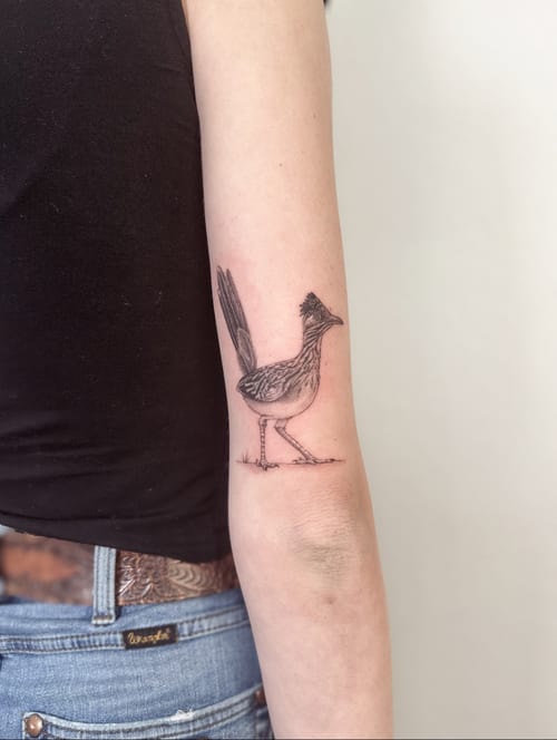 A delicate black and grey bird tattoo on the forearm, featuring an illustrative style with fine line details — by Melanie Benoit, los angeles