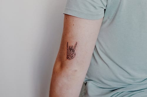 A minimalist linework tattoo of a skeleton hand on the arm, showing a simple and clean design — by Level tattoo, los angeles
