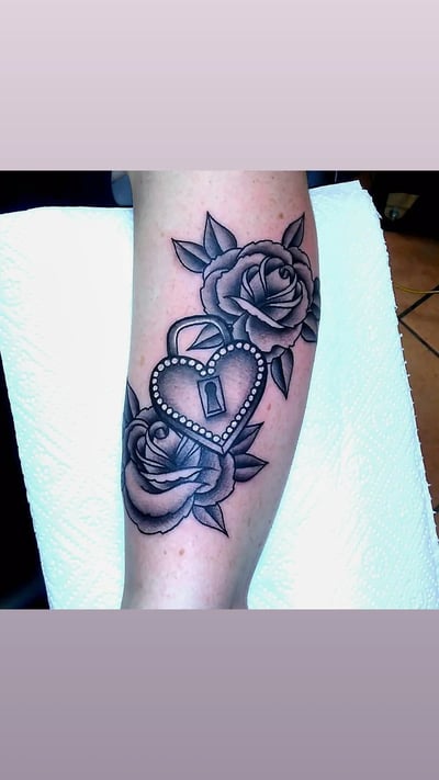 A bold black and grey tattoo of a heart lock surrounded by roses on the forearm — by Samuel Connelly, los angeles