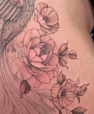 A delicate black and grey tattoo of a bird with flowers, featuring fine line details and ornate floral elements — by Melanie Benoit, los angeles