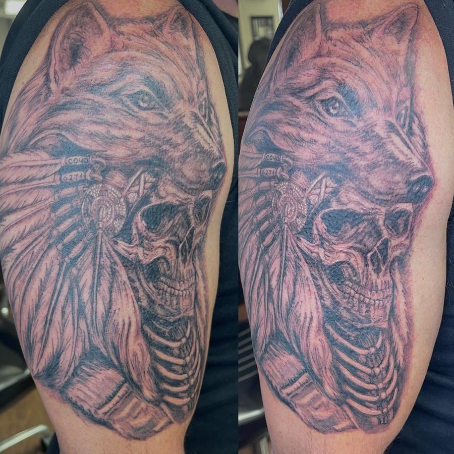 A bold black and grey tattoo of a wolf and skull on the upper arm, featuring realistic details and shading — by Sandra Price, los angeles