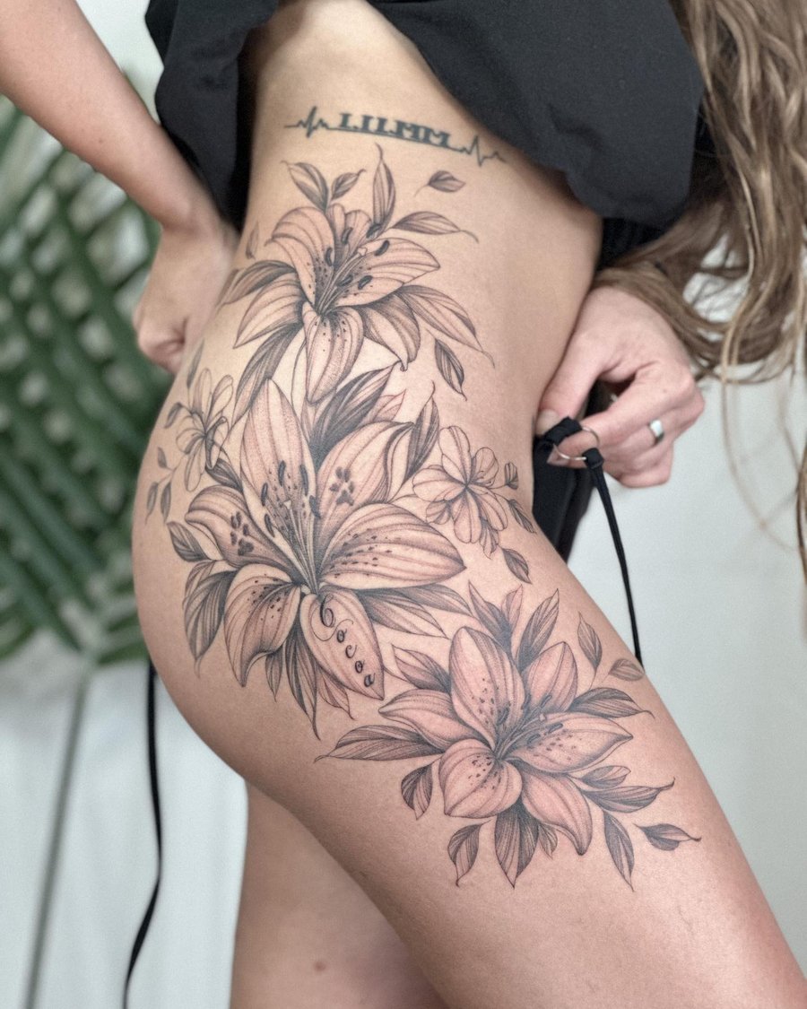 A delicate black and grey tattoo of lily flowers on the hip with intricate floral details — by Melanie Benoit, los angeles