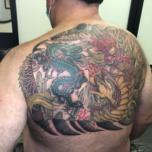 A colorful Japanese-style dragon tattoo covering the back with intricate details and bold colors — by Sandra Price, los angeles