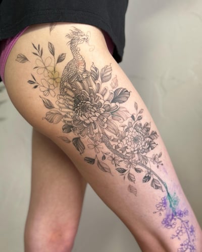 A black and grey dragon intertwined with flowers on the thigh, featuring delicate and ornate Japanese style elements — by Melanie Benoit, los angeles