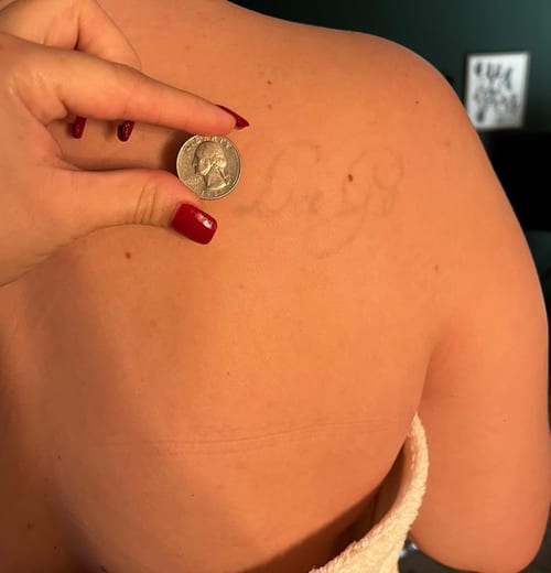 A faded script lettering tattoo on the back in a minimalist style — by Melanie Benoit, los angeles