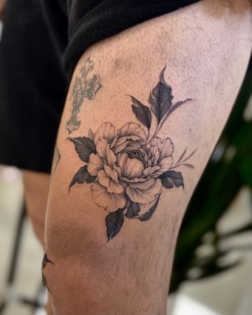 A black and grey fine line floral tattoo on the thigh, featuring a detailed flower with delicate shading — by otaybeatdown, los angeles