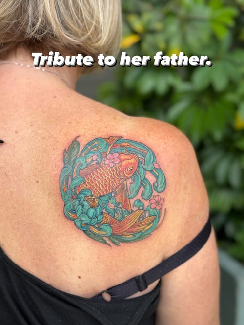 A colorful koi fish with floral elements tattooed on the back in a Japanese style, featuring ornate and delicate details — by Sandra Price, los angeles