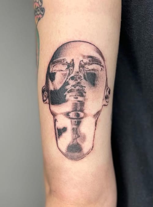 A surreal black and grey tattoo of a distorted face on the forearm, featuring abstract and reflective elements — by Level tattoo, los angeles