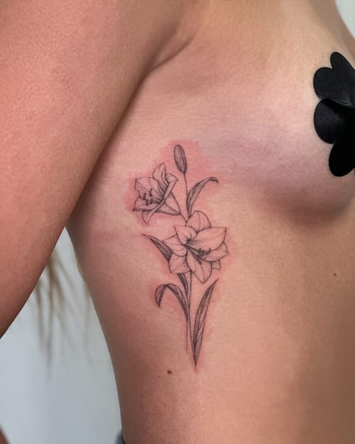 A delicate black and grey fine line tattoo of lily flowers on the rib, featuring minimalistic floral design — by Melanie Benoit, los angeles