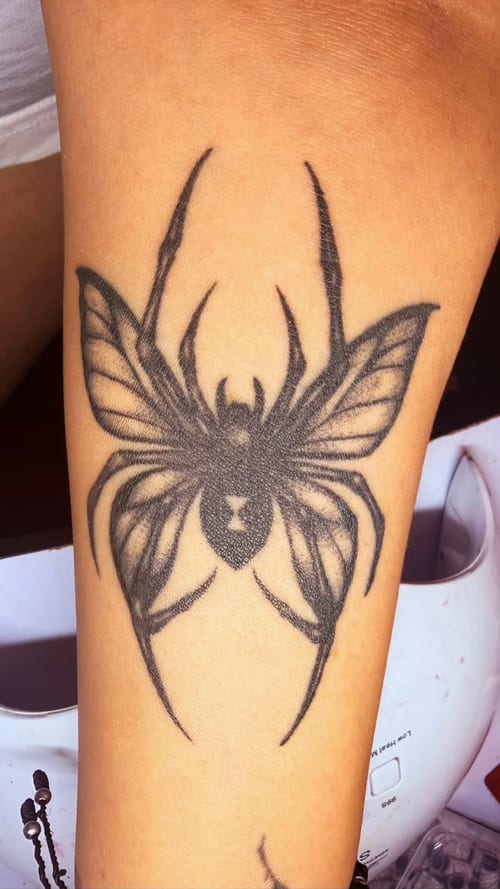 A black and grey linework tattoo of a spider on the forearm, featuring bold lines and symmetrical design — by anoetic.designs.ultd, los angeles
