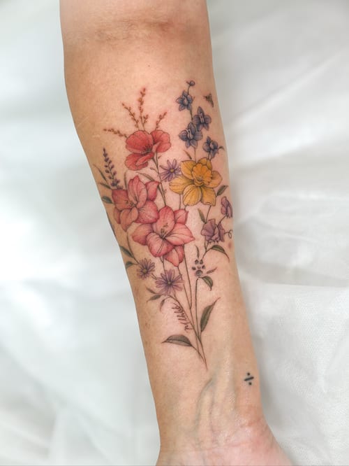 A delicate and colorful floral bouquet tattoo on the forearm, featuring fine line work and a variety of flowers — by Melanie Benoit, los angeles