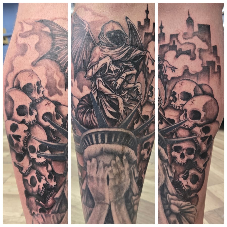 A detailed black and grey tattoo on the calf featuring a hooded figure with wings surrounded by multiple skulls and a cityscape in the background, creating a dark and atmospheric scene — by Dretty,…