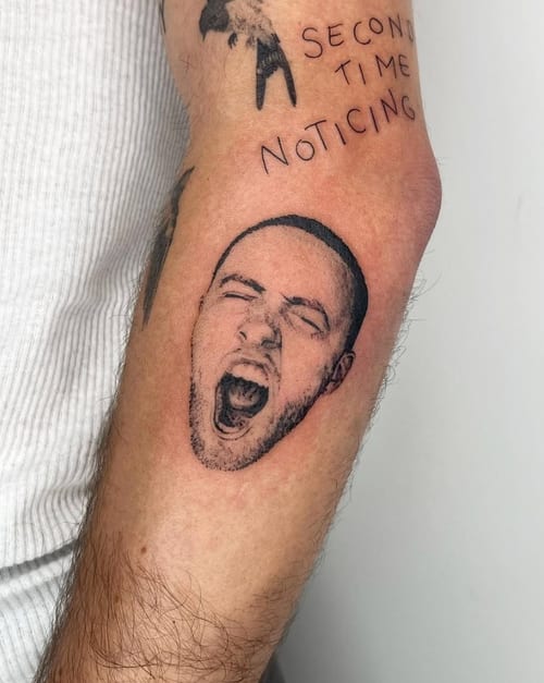 A black and grey portrait tattoo on the forearm depicting a person's face with an open mouth, rendered in a blackwork style — by Level tattoo, los angeles