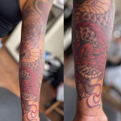 A bold and colorful Japanese-style snake with flowers tattoo on the forearm, featuring intricate scales and vibrant red flowers — by Sandra Price, los angeles