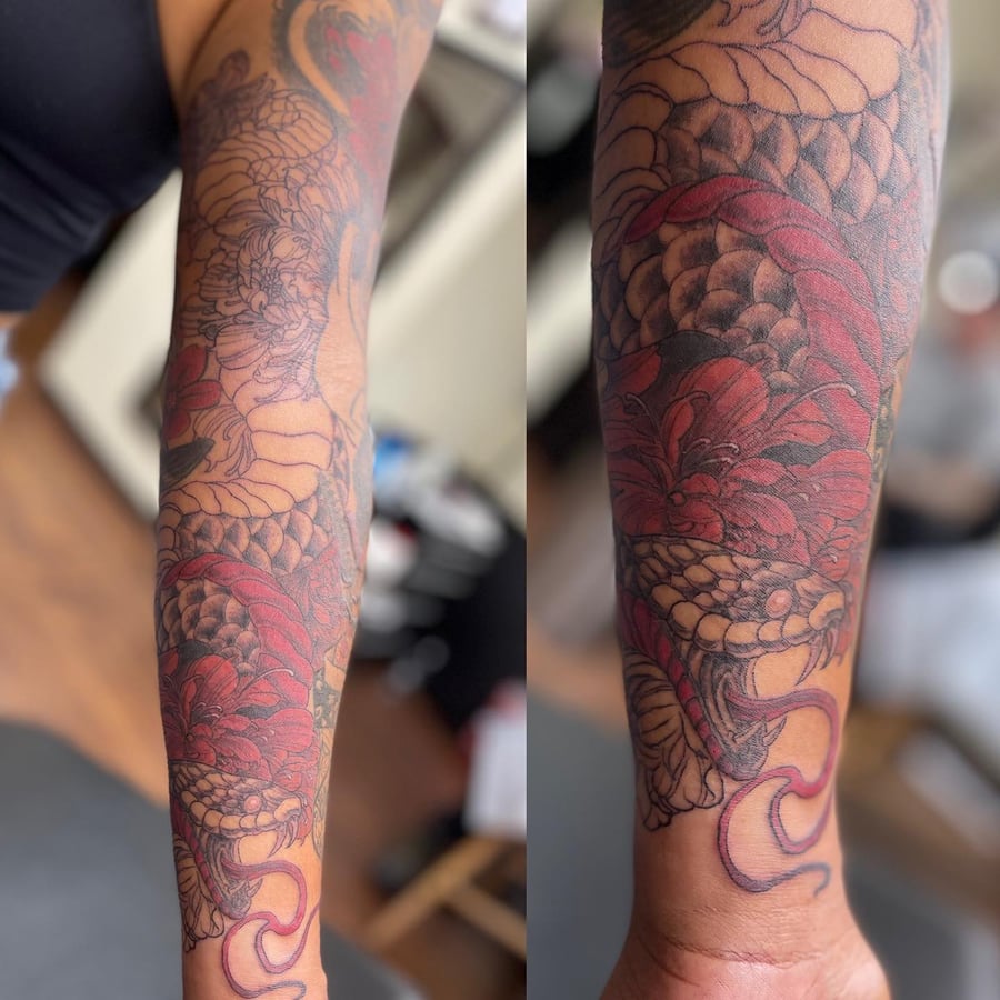 A bold and colorful Japanese-style snake with flowers tattoo on the forearm, featuring intricate scales and vibrant red flowers — by Sandra Price, los angeles