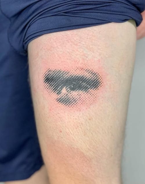 An abstract black and grey dotwork tattoo of a face on the thigh, featuring a pixelated effect — by Level tattoo, los angeles