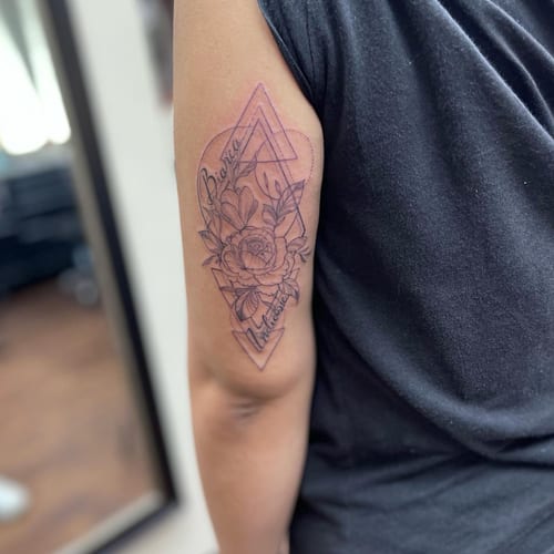 A delicate black and grey floral geometric tattoo on the upper arm with fine line details and script lettering — by Sandra Price, los angeles