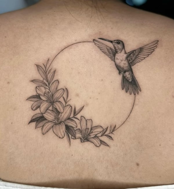 A fine line black and grey tattoo of a hummingbird and flowers on the back, featuring delicate linework and shading — by otaybeatdown, orange, ca