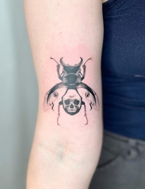 A black and grey surrealistic tattoo of an insect with a skull integrated into its body, located on the forearm — by Level tattoo, los angeles