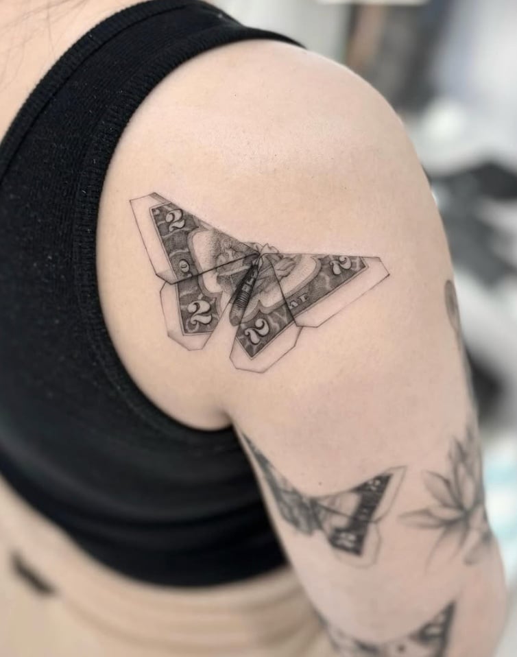 A black and grey realistic butterfly tattoo on the shoulder, featuring intricate details and shading — by otaybeatdown, los angeles