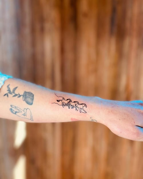 A minimalist linework tattoo of running horses on the forearm, using black ink for a delicate design — by Dylan Aiello, los angeles
