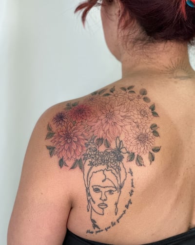 A delicate linework tattoo of a woman's face with colorful flowers on the back, combining floral and portrait elements — by Melanie Benoit, los angeles