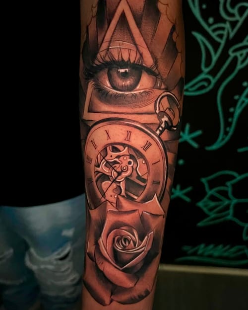 A detailed black and grey tattoo on the forearm featuring a realistic eye, a clock with Roman numerals, and a rose, all enclosed within geometric shapes — by Josue Bravo, los angeles
