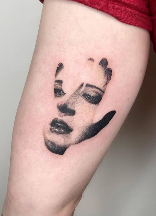 A black and grey realism tattoo of a woman's face integrated with a handprint on the thigh, featuring detailed shading and contrast — by Level tattoo, los angeles
