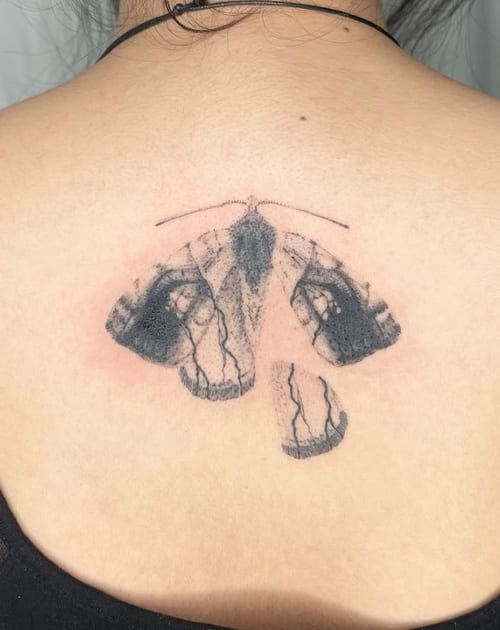 An abstract blackwork tattoo of a butterfly on the back, featuring bold lines and textured shading — by Level tattoo, los angeles