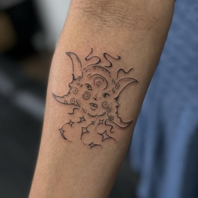 A fine line blackwork tattoo of a celestial face with crescent moons on the forearm — by Maddie Ramirez, los angeles