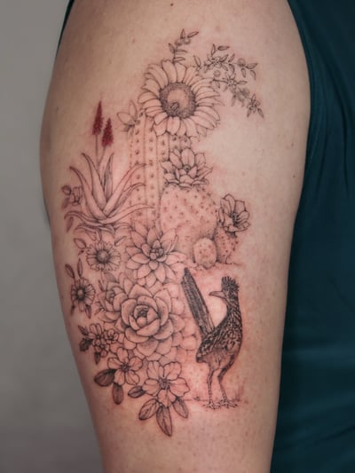 A delicate black and grey tattoo of a cactus and bird surrounded by flowers on the upper arm, featuring fine line and blackwork styles — by Melanie Benoit, los angeles