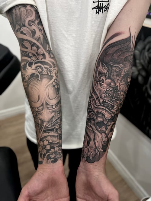 Black and grey Japanese-style tattoos on both forearms featuring traditional masks and floral elements with intricate shading — by imindisoul, los angeles