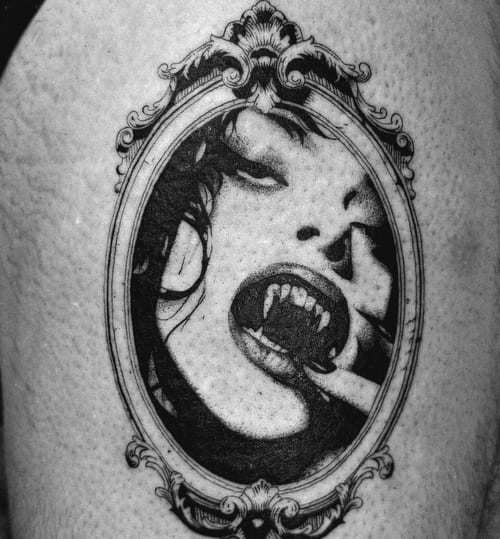A black and grey portrait of a woman with vampire fangs in an ornate frame, showcasing detailed realism and shading — by NJ TATTOOZ, los angeles