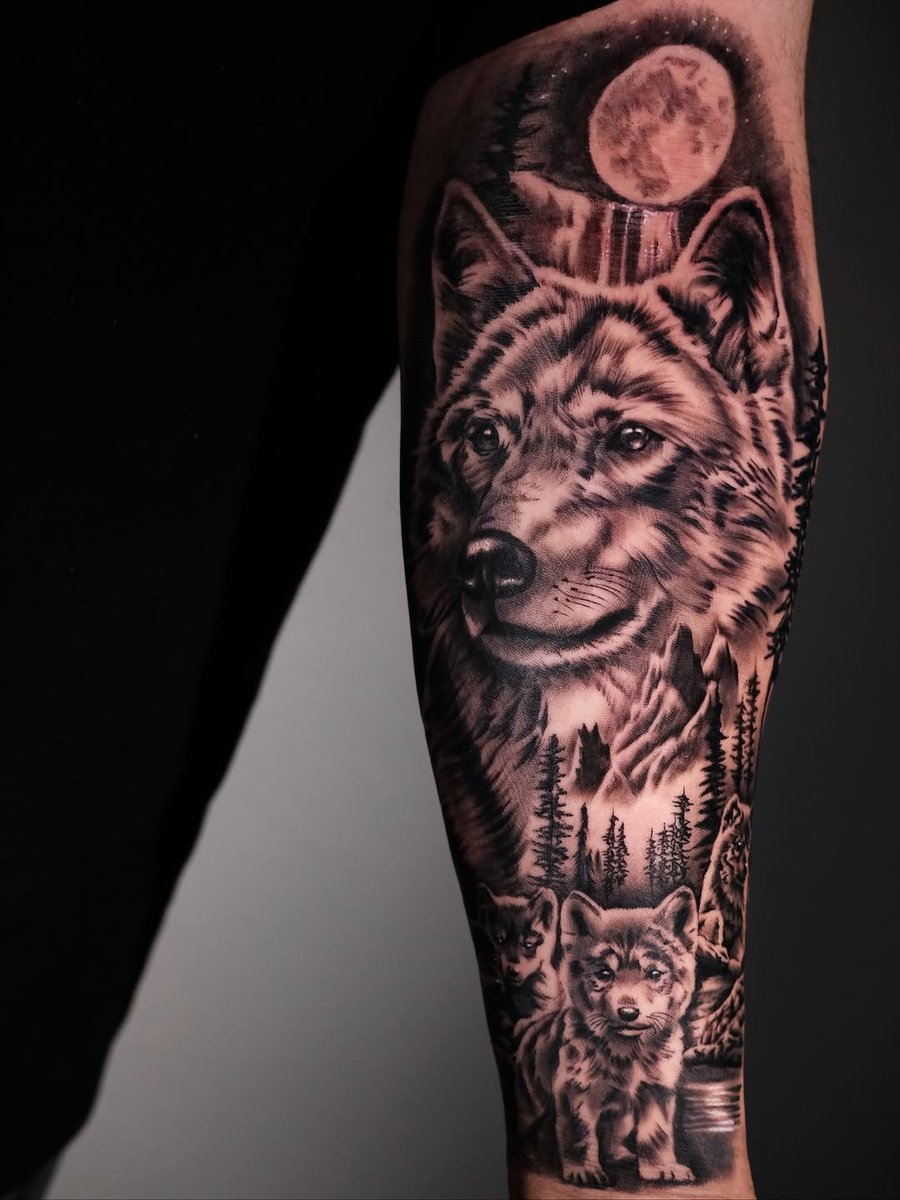 A detailed black and grey wolf tattoo on the forearm, featuring a moon and forest background — by Johnny Ayala, los angeles
